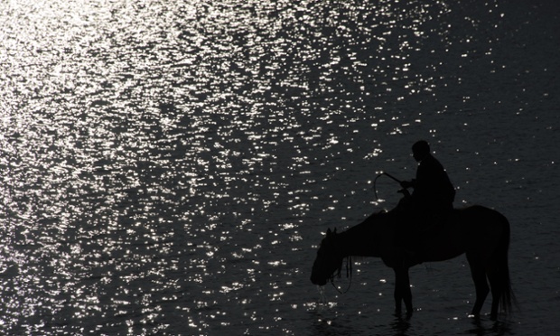 An Afghan youth sits on his horse as it drinks from the Qargha lake near Kabul.