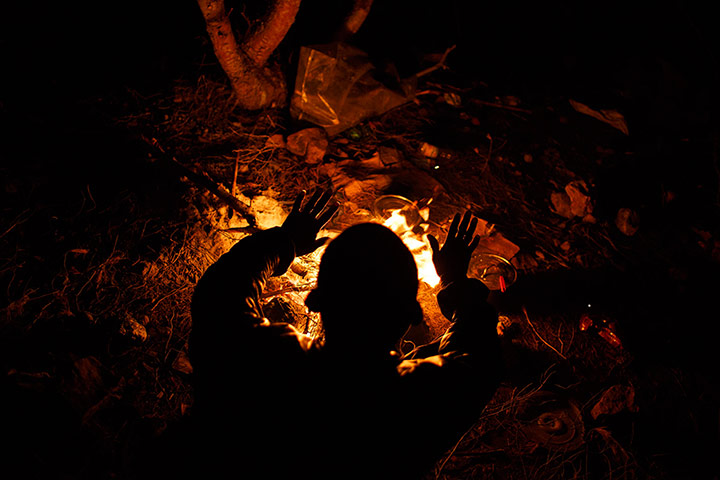 Melilla: An African migrant warms himself by a fire at a clandestine campsite