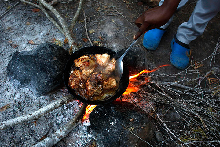 Melilla: A migrant from Cameroon cooks food at a clandestine campsite