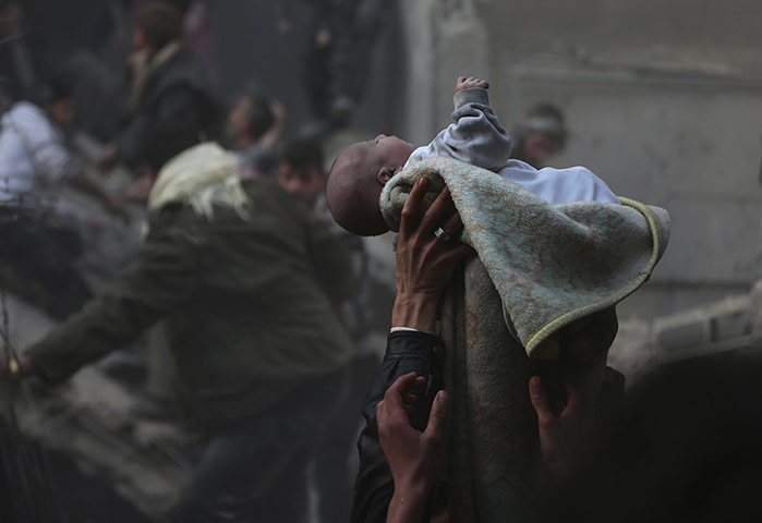 20 Photos: Men hold up a baby rescued from rubble caused by an airstrike in Damascus
