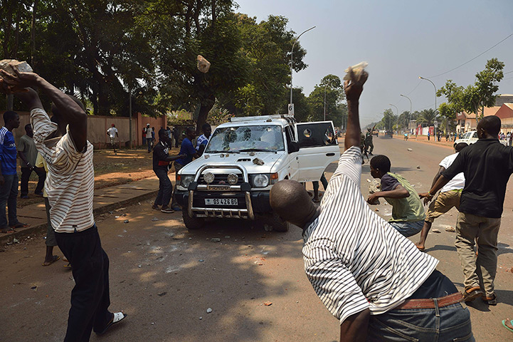 Weekend in pictures: Bangui., Central African Republic: People throw stones at a car transportin