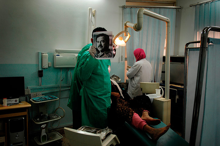 big picture - iraq flying: Iraqi doctor holding up picture of Saddam Hussein