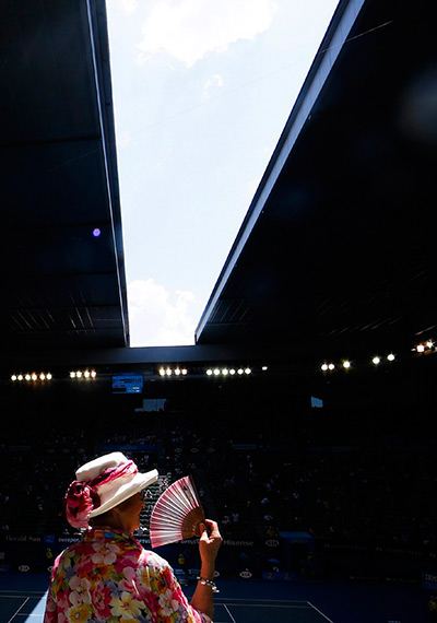 Australian Open heat: A woman cools off with a fan as the roof of the Rod Laver Arena is being cl