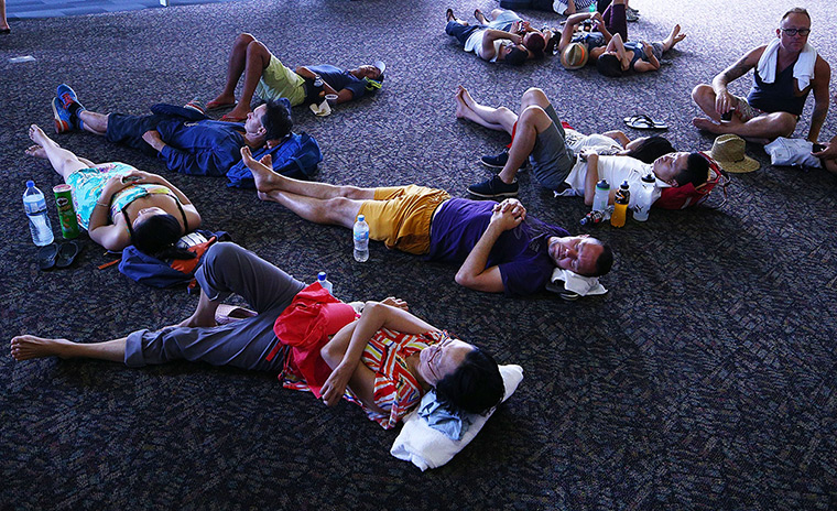 Australian Open heat: Tennis fans escape the heat by resting on the concourse floor of Hisense Ar