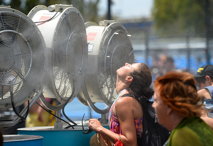 Australian Open heat: A woman cools off with fans and mist put out for spectators as a heat wave 