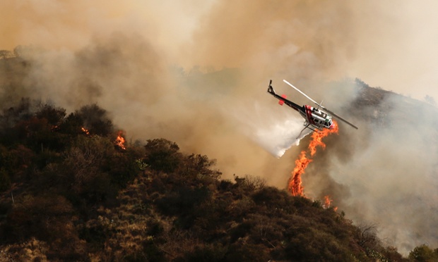 A helicopter drops water over a wildfire burning out of control near homes in the dangerously dry foothills of the San Gabriel Mountains , California.
