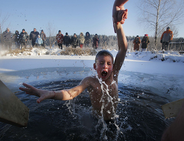 Weekend in pictures: Zadomlya, Belarus: A boy reacts in the ice cold water after plunging into i