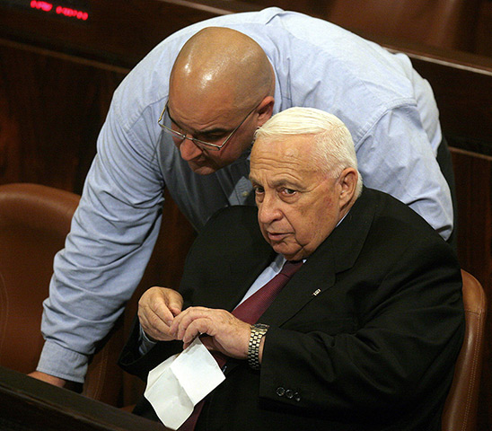 Ariel Sharon in pictures: 2004: Prime Minister Ariel Sharon listens to his son Omri during a Knesset 