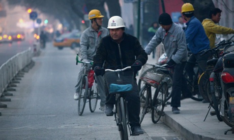 This picture taken on January 15, 2014 shows a group of Chinese workers riding bicycles outside a construction site in Beijing.
