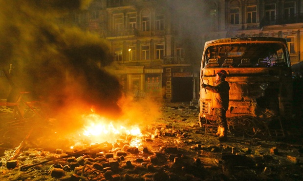 A protester gestures near a burned car as ro-European integration protesters clashed with riot police in Kiev, Ukraine. See more images in our gallery.