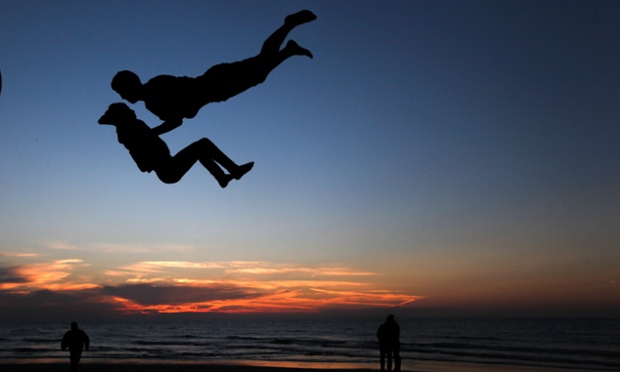 Floating? A Palestinian youth performs stunts at the beach of Gaza City with his friends during sunset