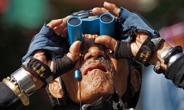 A security guard scans rooftops during anti-government marches in Bangkok, Thailand.