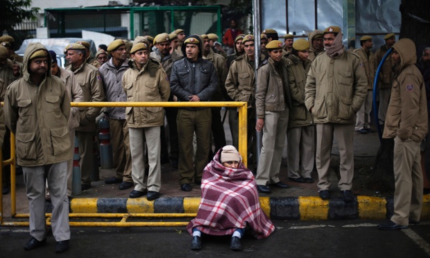 A supporter of New Delhi Chief Minister Arvind Kejriwal, sits as police stand guard during a demonstration in New Delhi, India.