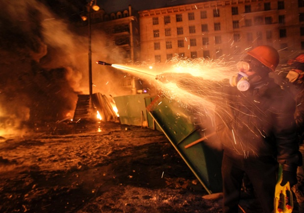 A protester fires off fireworks towards riot police.