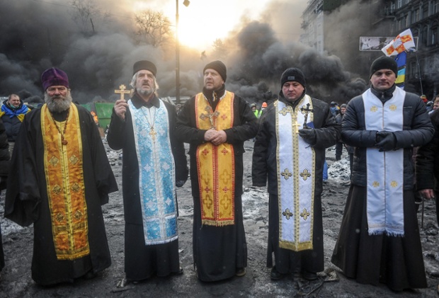 Priests stand in front of the burning barricades. At least two people died of gunshot wounds and a demonstrator also reportedly fell to his death after being chased by police on Wednesday
