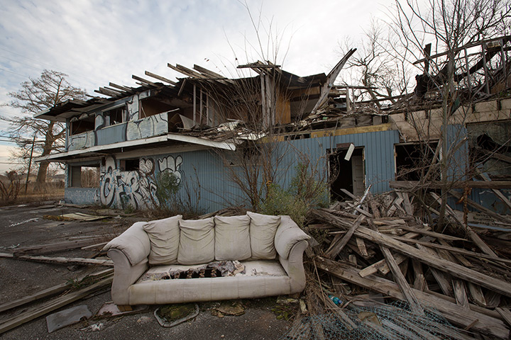 Rebuilding New Orleans: A discarded couch in front of an abandoned partially burnt-down building 