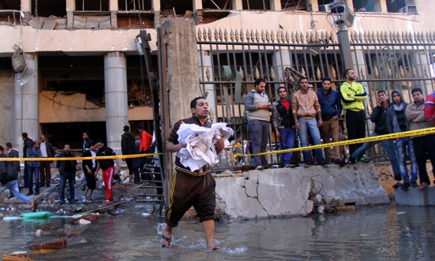 An Egyptian man carries paperwork away from the building. A crude device exploded near a police station in a Cairo suburb, security sources said, hours after a car bomb killed at least four people near the Egyptian police headquarters in the center of the Egyptian capital.