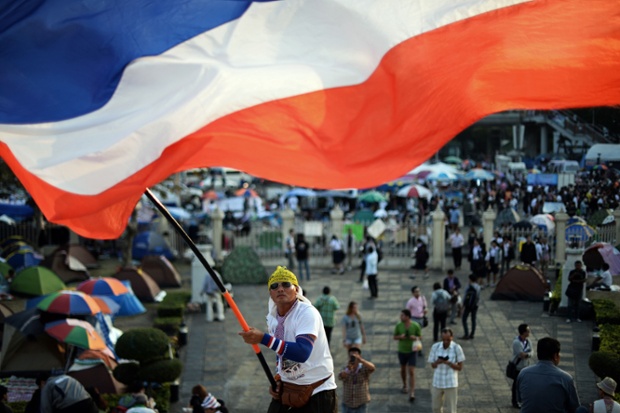 A Thai anti-government protester waves a national flag during ongoing rallies at a protest site at Victory Monument in downtown Bangkok.