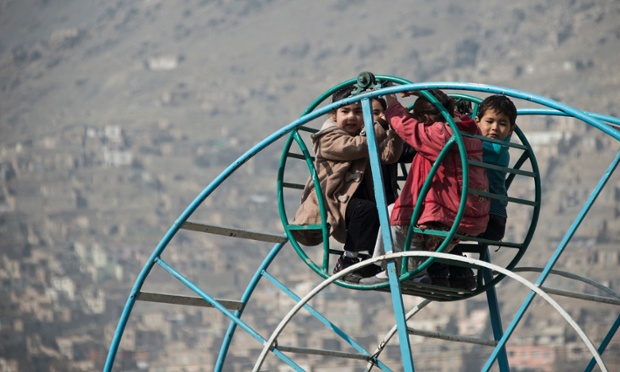 Afghan children ride on a ferris wheel near a cemetery in Kabul.