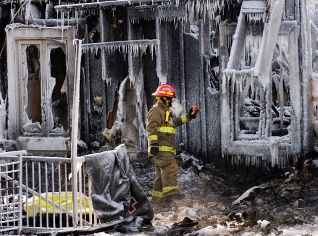 A firefighter checks for gas leaks as rescue personnel search through icy rubble to try to locate more victims of a fire that destroyed a seniors' residence in L'Isle-Verte, Quebec.