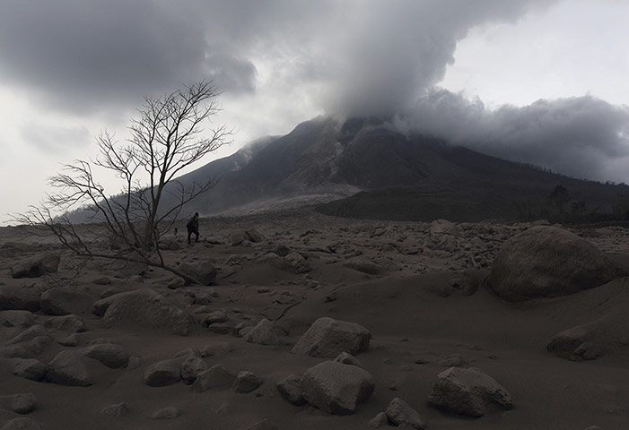20 Photos: A photographer stands on ash from the eruption of Mount Sinabung