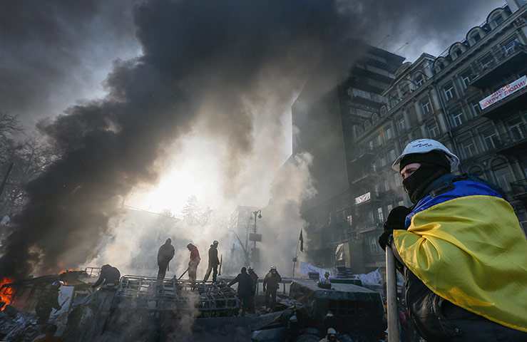 Protests in Ukraine: A protester wearing a Ukrainian national flag stands on a barricade in Kiev