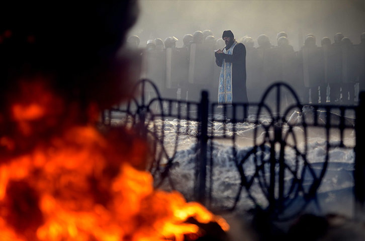 Protests in Ukraine: A priest prays in front of the riot police in Kiev