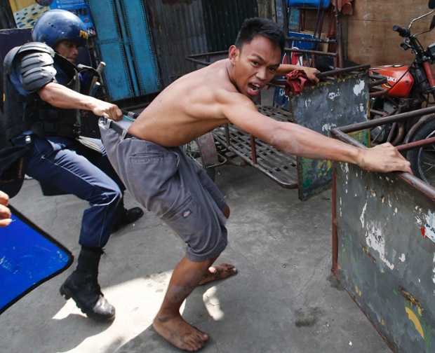 A policeman detains a squatter dweller during clashes in Quezon city, Manila. Dozens were hurt during clashes triggered by the demolition of a squatter settlement to make way for business developments.