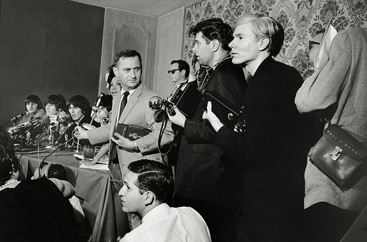 Beatles in America: Andy Warhol waits amongst the photographers at a Beatles press conference in N