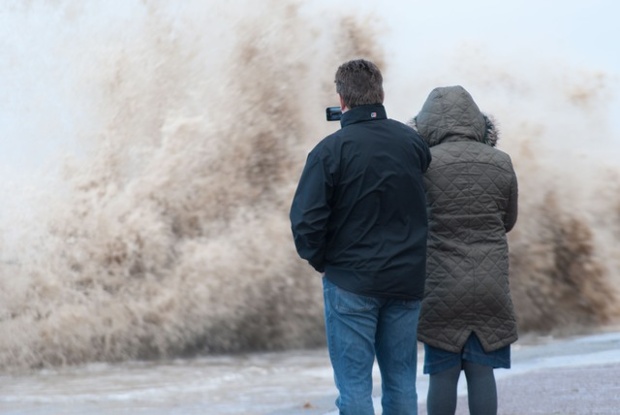 A man and a woman watch the waves at North Parade, Hoylake, Wirral at high tide on Friday lunchtime.