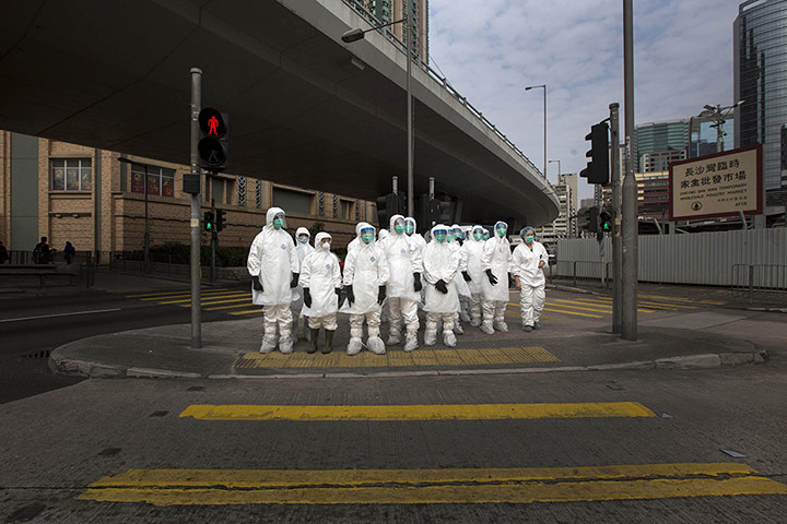 20 Photos: Health officers wait to cross a road near a poultry market in Hong Kong