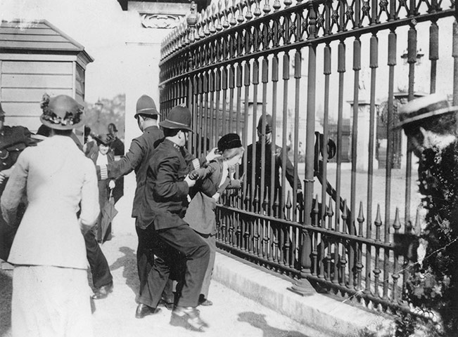 Before the war: A police officer tries to remove a Suffragette from railings 