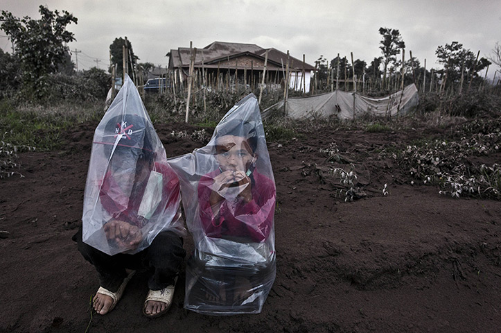 Mount Sinabung: Two boys wear plastic bags to protect themselves from ash 