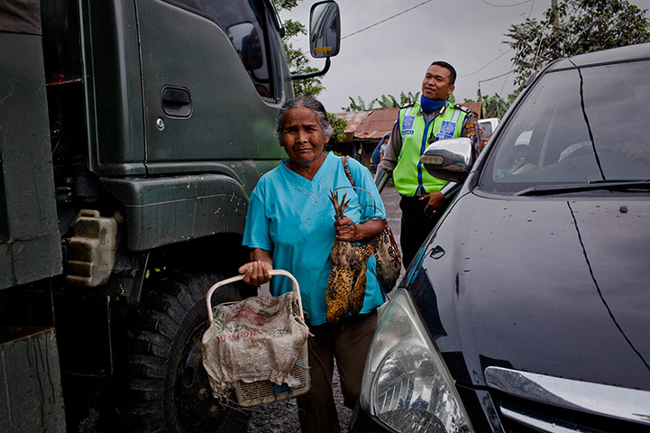 Mount Sinabung: A woman carries provisions as residents are evacuated from their village to