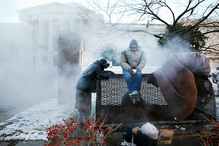Weekend in pictures: Four homeless men warm themselves on a steam grate by the Federal Trade Com