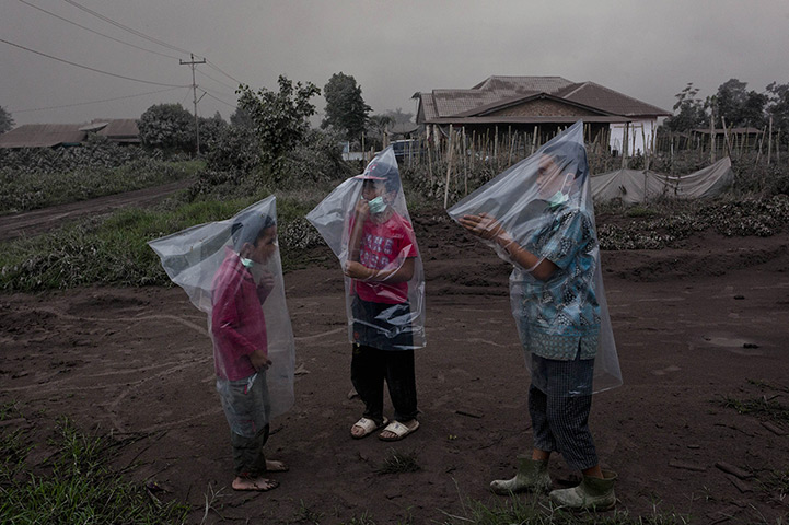 Weekend in pictures: Children wear plastic bags to protext themselves from ash following a furth