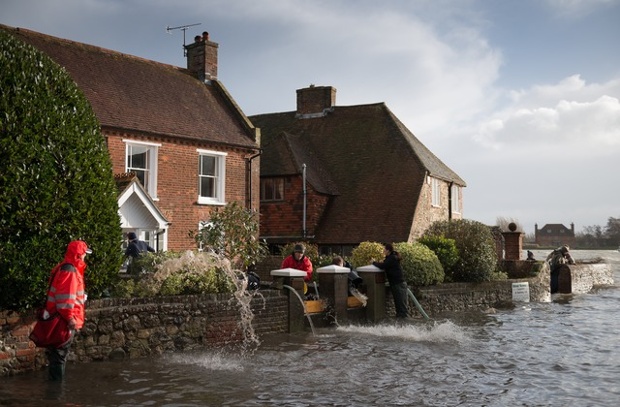 A postman waiting to do his rounds as residents bail water during high spring tide flooding in the village of Bosham.
