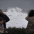 Stormy weather: People take pictures of a wave hitting t