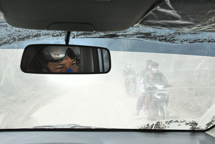 Mount Sinabung volcano: A man is reflected in the mirror of a car during an ash fall