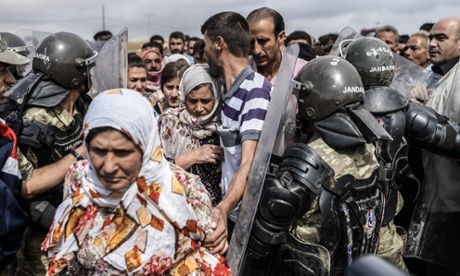 Turkish soldiers filter access at the Mursitpinar crossing gate as Syrian Kurds try to pass back into Syria.