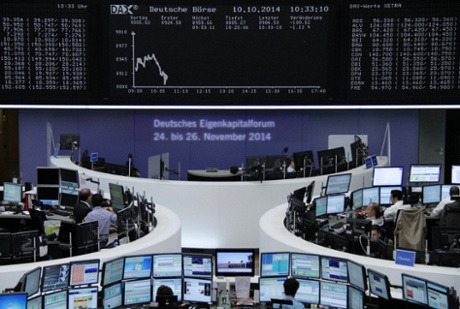 Traders are pictured at their desks in front of the DAX board at the Frankfurt stock exchange October 10, 2014.