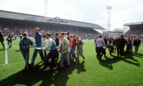 Supporters use advertising boards to carry injured fans out of Hillsborough stadium. The police clai