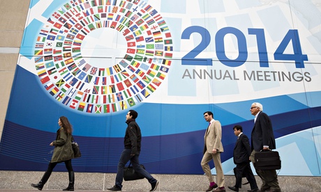People walk past a sign for the World Bank/IMF annual meetings in Washington