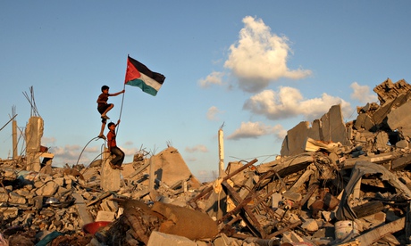 Palestinian children in Khan Yunis on the Gaza Strip place their national flag on the rubble of a bu