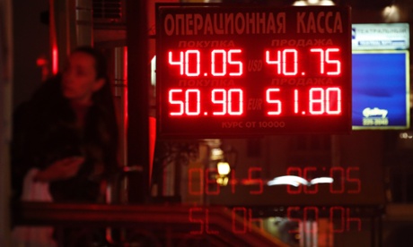 A woman enters a building with a board showing currency exchange rates in Moscow. Photo: Reuters/Tatyana Makeyeva