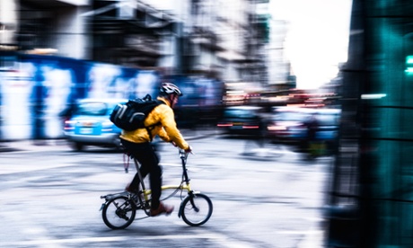 Cyclist wearing a bright Yellow jacket is taking a right turn into Tottenham Court Road, London