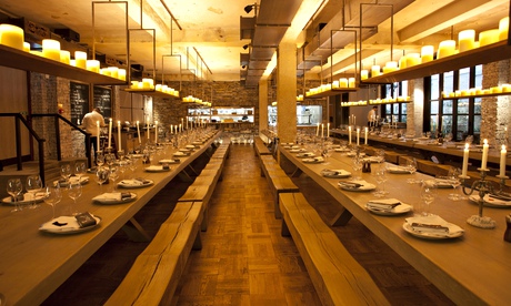 Long communal tables with benches and candles on a hanging shelf at Beast