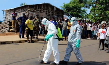 Health workers spray themselves with chlorine disinfectants after removing the body a woman who died of Ebola virus in Freetown, Sierra Leone.