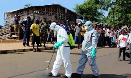 Health workers spray themselves with chlorine disinfectants after removing the body a woman who died of Ebola virus in the Aberdeen district of Freetown, Sierra Leone.