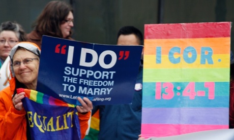Lin Davis, of Juneau, Alaska, shown wearing an orange rain coat, holds signs supporting gay marriage during a news conference in Anchorage.